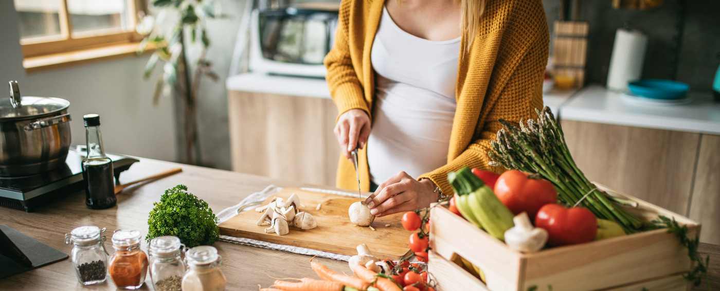 Humana schwangere Mama schneidet Gemüse